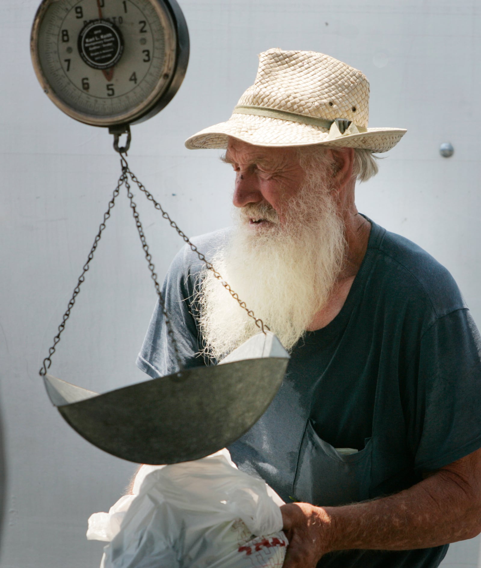 Garber Farm owner, Russell Garber, from west of Greenville, weights produce at his stand at the Miamisburg Farmer's Market in 2010.  Jim Noelker/Dayton Daily News