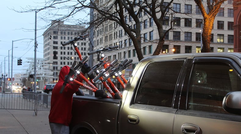 Spin scooters were removed from downtown Dayton on Feb. 1. A man is seen here near the Greater Dayton RTA hub loading the electric scooters into the back of a truck. CORNELIUS FROLIK / STAFF
