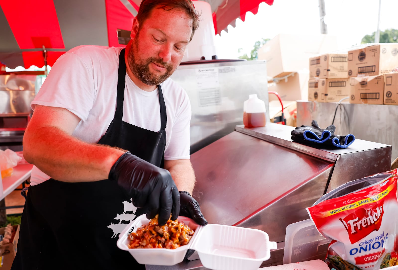 Brian Garver makes a mac and cheese bowl at Liberty's Best, a combination of The Produce Stand and Farmhouse Grill,  at the Butler County Fair with a variety of salads, breakfast items, burgers, mac and cheese combos, crepes, fruit juices and more. NICK GRAHAM/STAFF