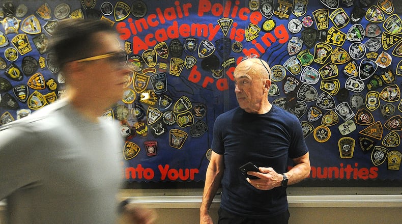Retired chief and instructor David Miller keeps a stopwatch for cadets running through the halls at Sinclair Community College. MARSHALL GORBY\STAFF