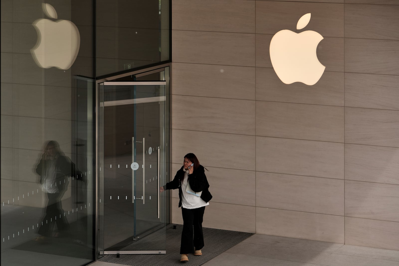 A woman walks out from an Apple Store at an outdoor shopping mall in Beijing, Tuesday, April 8, 2025. (AP Photo/Andy Wong)