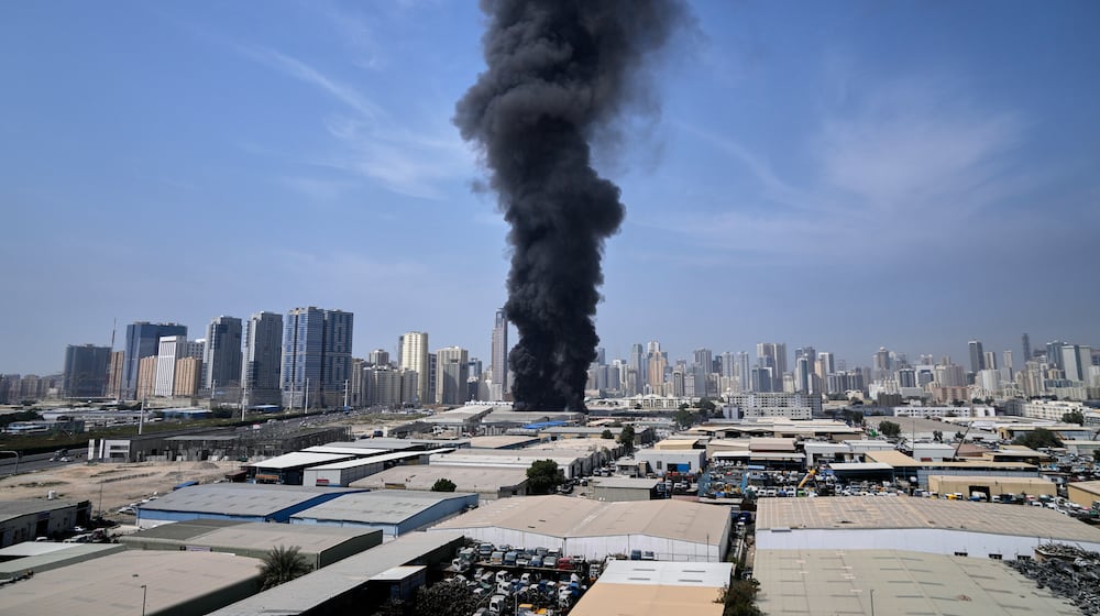 A black plume of smoke rises from a warehouse at the industrial area of Sharjah City in the United Arab Emirates following reports of Iranian strikes in Dubai, United Arab Emirates, Sunday, March 1, 2026. (AP Photo/Altaf Qadri)