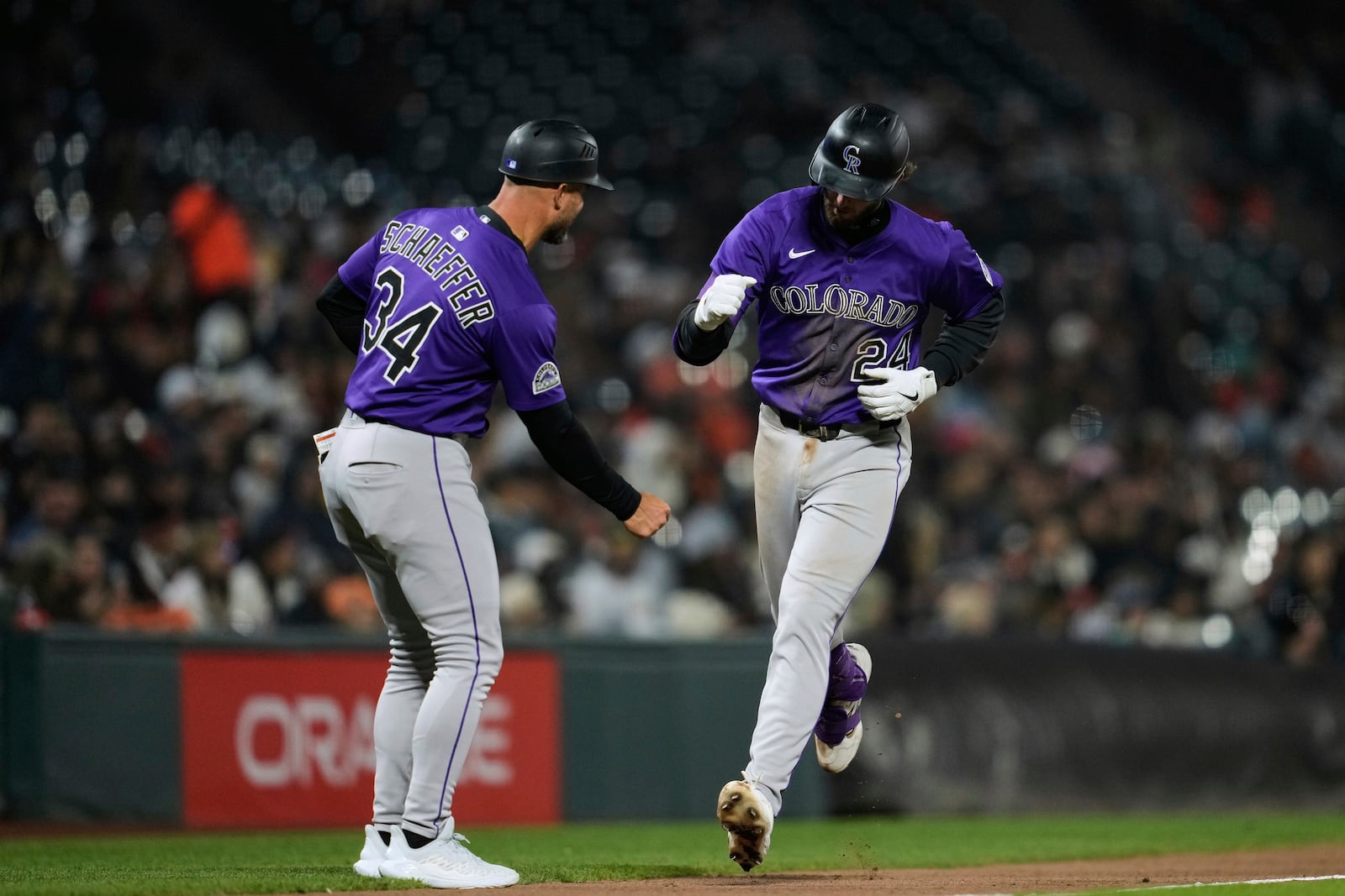 Colorado Rockies' Ryan McMahon (24) celebrates with third base coach Warren Schaeffer after hitting a solo home run during the seventh inning of a baseball game against the San Francisco Giants, Thursday, May 1, 2025, in San Francisco. (AP Photo/Godofredo A. Vásquez)