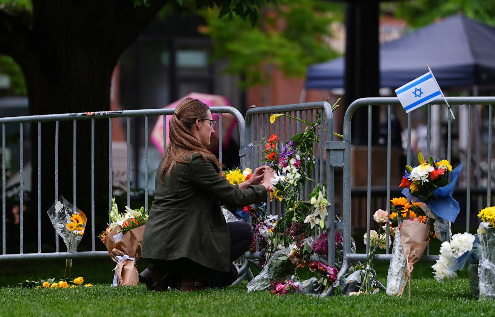 A woman places a bouquet of flowers at a makeshift memorial for victims of an attack outside of the Boulder County, Colo., courthouse Tuesday, June 3, 2025, in Boulder, Colo. (AP Photo/David Zalubowski)