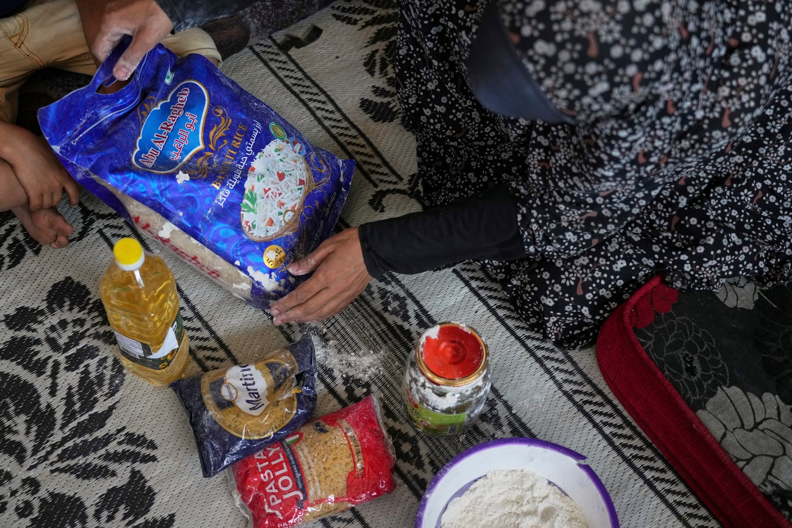 Anwaar Saleh, 32, displays the donated food her husband, Omar al-Hobi, collected at a distribution center run by private contractor the Gaza Humanitarian Foundation in the southern Gaza Strip, after he arrived at their family's tent in Khan Younis, Tuesday, June 10, 2025. (AP Photo/Abdel Kareem Hana)
