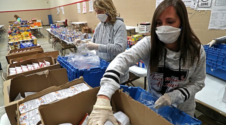 Staff and volunteers at Tecumseh High School, including Natalie Jackson, right, spent the afternoon filling food bags for students with food the community donated. BILL LACKEY/STAFF