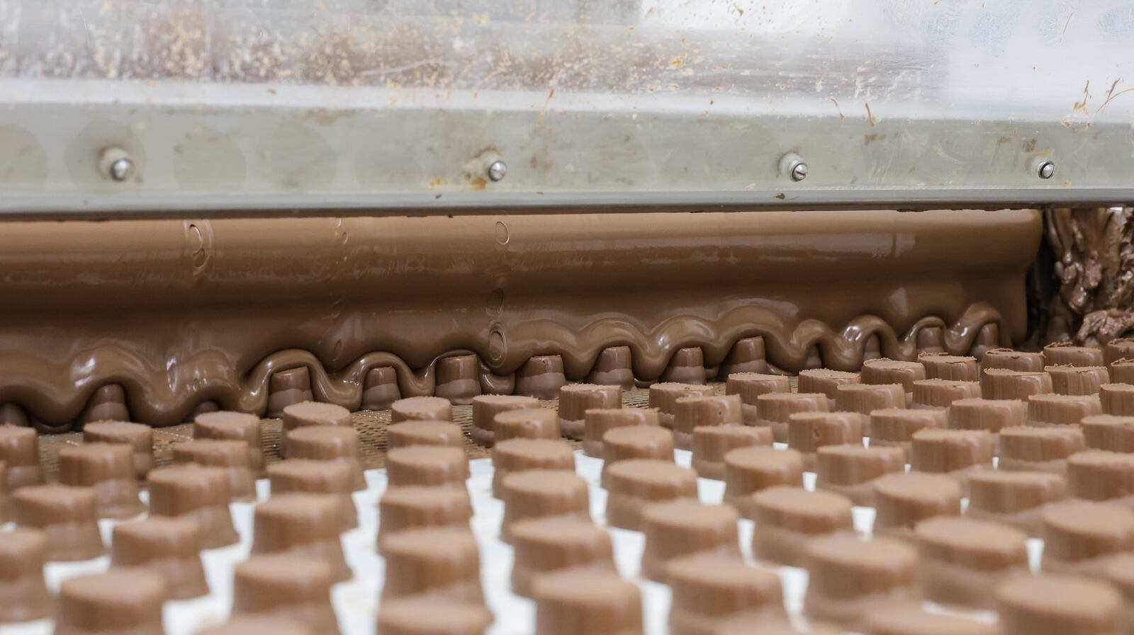 Pieces of fudge used for some Esther Price candies rolls on a conveyor belt at the company's production facility on Wayne Avenue on Tuesday, March 3. The company is celebrating its 100th anniversary. BRYANT BILLING / STAFF