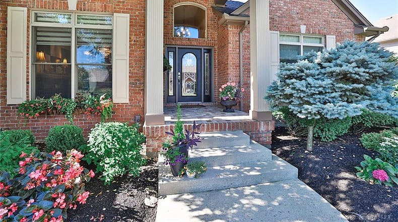 The brick and cedar home has a two story covered entry with a tile covered brick front porch.