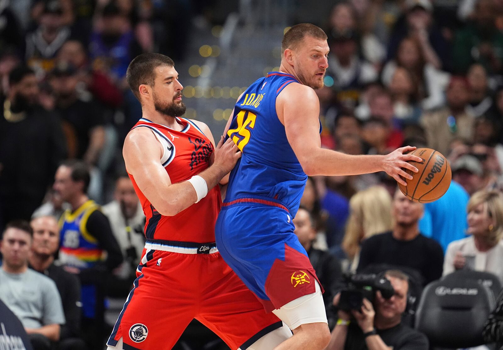 Denver Nuggets center Nikola Jokic, right, looks to pass the ball as Los Angeles Clippers center Ivica Zubac, left, defends in the second half of Game 1 of an NBA first-round playoff series Saturday, April 19, 2025, in Denver. (AP Photo/David Zalubowski)