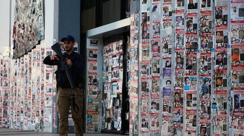 A police officer walks past posters of missing persons in front of the Special Prosecutor's Office for Missing Persons in Guadalajara, Mexico, Wednesday, Feb. 25, 2026. (AP Photo/Marco Ugarte)