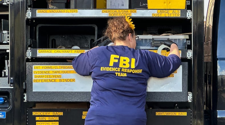 An FBI agent stands by an Evidence Response Team truck outside a home in a Dearborn, Mich., neighborhood on Friday, Oct. 31, 2025. (AP Photo/Mike Householder)
