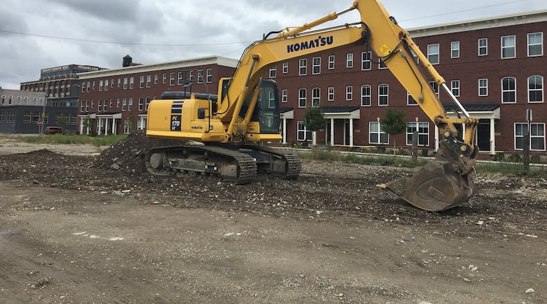 An excavator sits on the land between the commercial buildings on the 600 block of East Third St. and the Brownstones at 2nd townhouses. The land will become a parking lot to benefit redevelopment of the commercial buildings. CORNELIUS FROLIK / STAFF