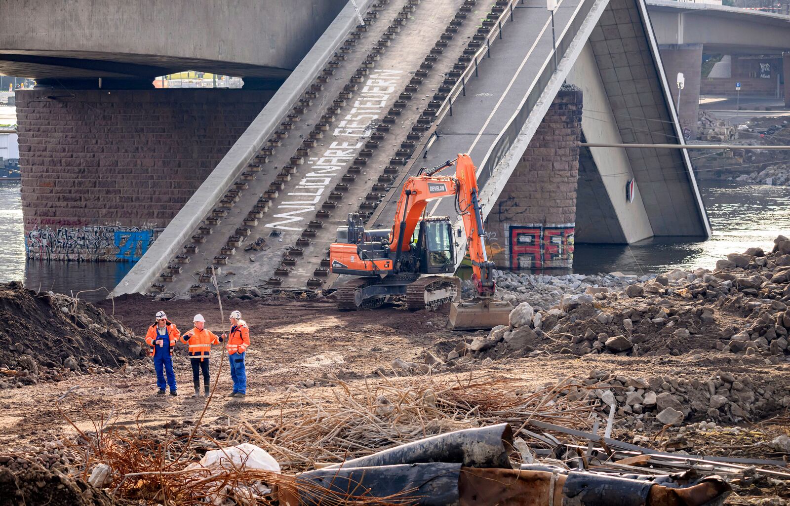 FILE - Experts stand in front of an excavator on the partially collapsed Carola Bridge on the Neustadt side during works, in Dresden, Germany, Thursday Jan. 30, 2025. (Robert Michael/dpa via AP, File)
