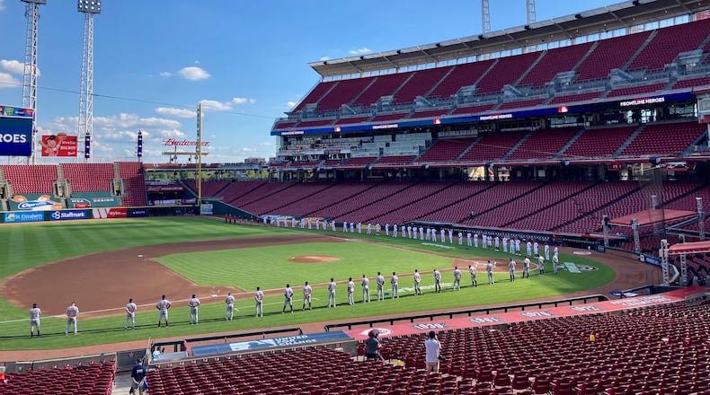 The Reds and Tigers stand during pregame ceremonies on Opening Day on Friday, July 24, 2020, at Great American Ball Park in Cincinnati.