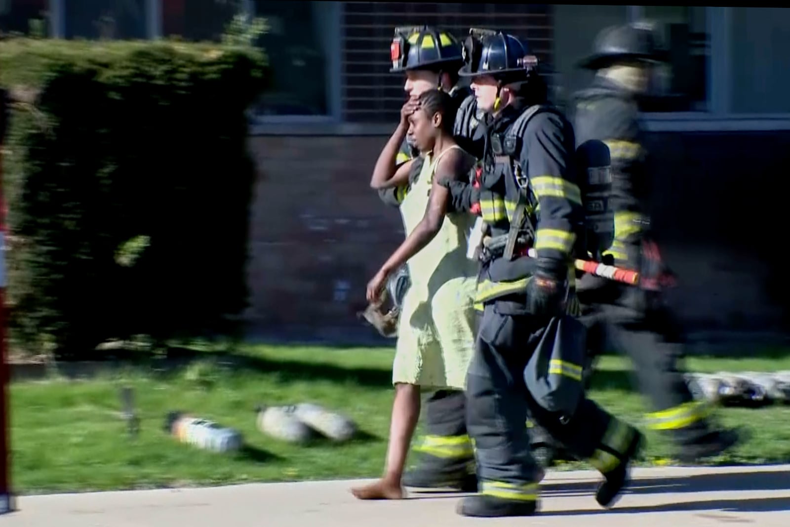 This image taken from video provided by WISN show a resident being escorted by firefighters at the site of an apartment building fire in Milwaukee, Wis., Sunday, May 11, 2025. (WISN via AP)