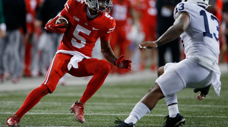 Ohio State receiver Garrett Wilson, left, runs after catching a pass against Penn State linebacker Ellis Brooks during the first half of an NCAA college football game Saturday, Oct. 30, 2021, in Columbus, Ohio. (AP Photo/Jay LaPrete)