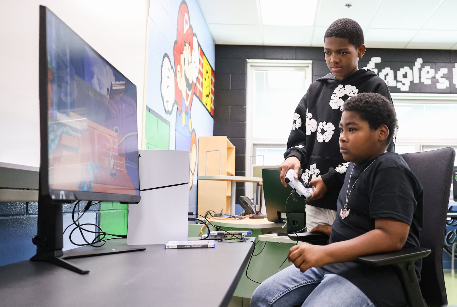 Eris Cosby (top) plays a Sonic video game on Playstation 5 in the game room at Westwood Elementary School while Tyrone Gullatte watches on Thursday, Sept. 4 in Dayton. Cosby and Gullatte are both sixth graders and among students who played in the room in its first week after being unveiled. BRYANT BILLING / STAFF