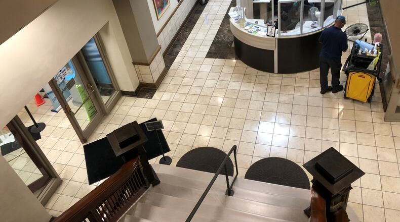 A sanitation worker cleans the front desk area at Dayton City Hall. CORNELIUS FROLIK / STAFF