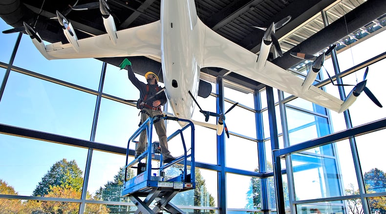 Owen Flannery, an employee with the city of Springfield, cleans the electric vertical take off and landing aircraft (eVTOL) that hangs in the lobby of the new National Advanced Air Mobility Center of Excellence at Springfield-Beckley Municipal Airport on Thursday, Sept. 14, 2023. BILL LACKEY/STAFF