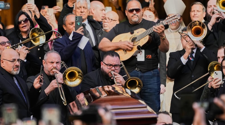 Musicians, primarily trombonists, play music as the body of Willie Colon leaves St. Patrick's Church during in New York, Monday, March 9, 2026. (AP Photo/Seth Wenig)