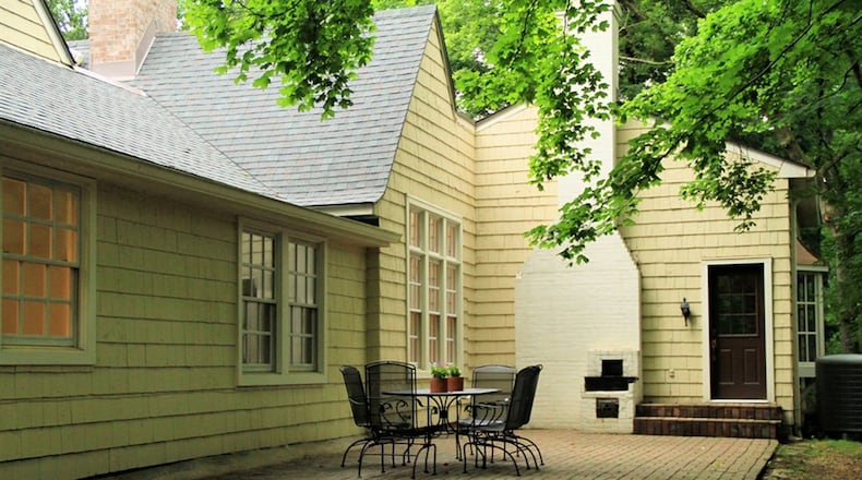 Another paver patio extends along the back of the home with a wide view of the private wooded area at its edge.