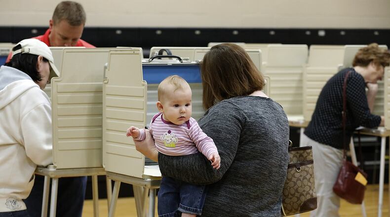 Five-month-old Margaret Russell looks around gymnasium at Tecumseh High School as her mother holds her while casting her vote at the election poll there. Bill Lackey/Staff