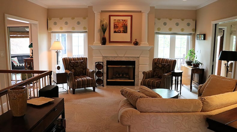 Inset neutral carpet extends from the entry’s edge into the open great room, where the fireplace is faced in marble, and the custom-designed mantel extends to the ceiling with columns and moldings to create an art niche.