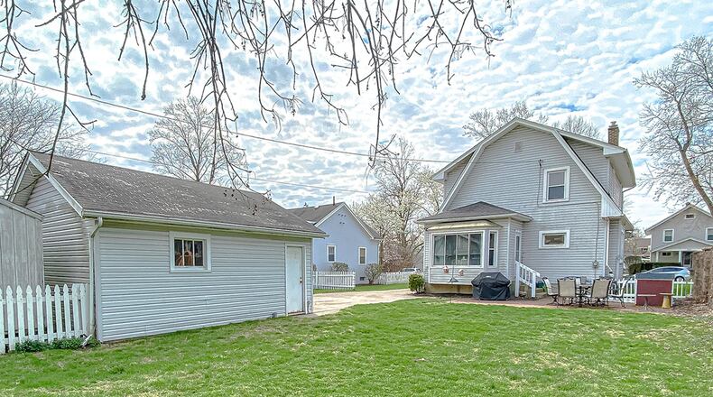 A bay-like breakfast room has a panoramic view of the deep back yard surrounded by stone, wood and picket fences.