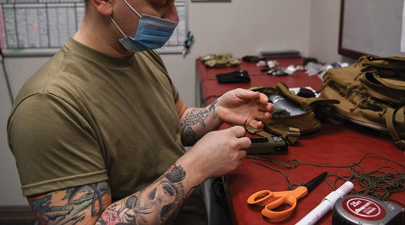 Staff Sgt. Brett Schindler, NCO in charge of the aircrew flight equipment shop’s helmets and chemical defense gear section at the 445th Operations Support Squadron, ties a lanyard to secure an escape-and-evasion kit inside an aircrew survival backpack at Wright-Patterson Air Force Base on Feb. 12. The gear is used for aircrew survival during an emergency when they need to evacuate the aircraft. U.S. AIR FORCE PHOTO/PATRICK O’REILLY