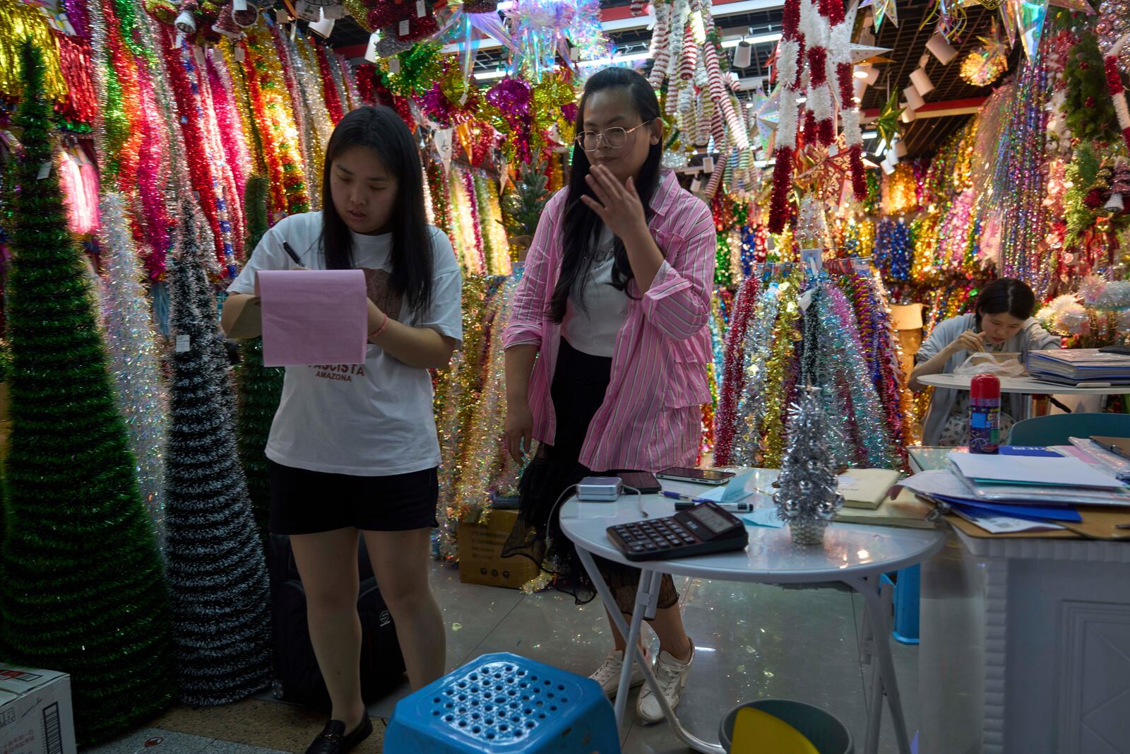 Ding Dandan, who runs Christmas decorations exports, at right gestures near her staff at the Yiwu International Trade Market in Yiwu, eastern China's Zhejiang province on Thursday, April 10, 2025. (AP Photo/Ng Han Guan)