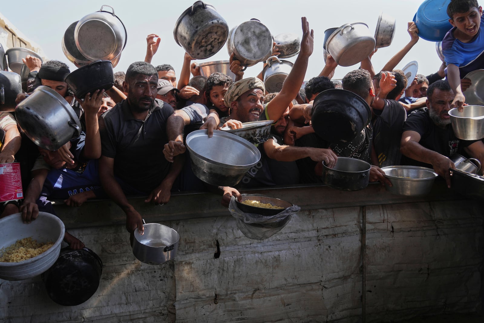 Palestinians struggle to obtain donated food at a community kitchen in Khan Younis, in the southern Gaza Strip, Friday, May 9, 2025. (AP Photo/Abdel Kareem Hana)