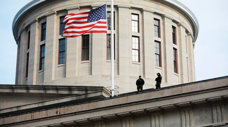 FILE - In this Jan. 13, 2021 file photo, fwo Ohio State Highway Patrol troopers look out from the Ohio Statehouse roof in Columbus.  Republican lawmakers in Ohio on Thursday, June 24, have moved to approve a bill banning transgender girls from participating in female sports teams in high school or college. The proposal, titled the Save Women’s Sports Act, would require schools and higher education institutions in the state to designate “separate single-sex teams and sports for each sex.”   (Doral Chenoweth/The Columbus Dispatch via AP)