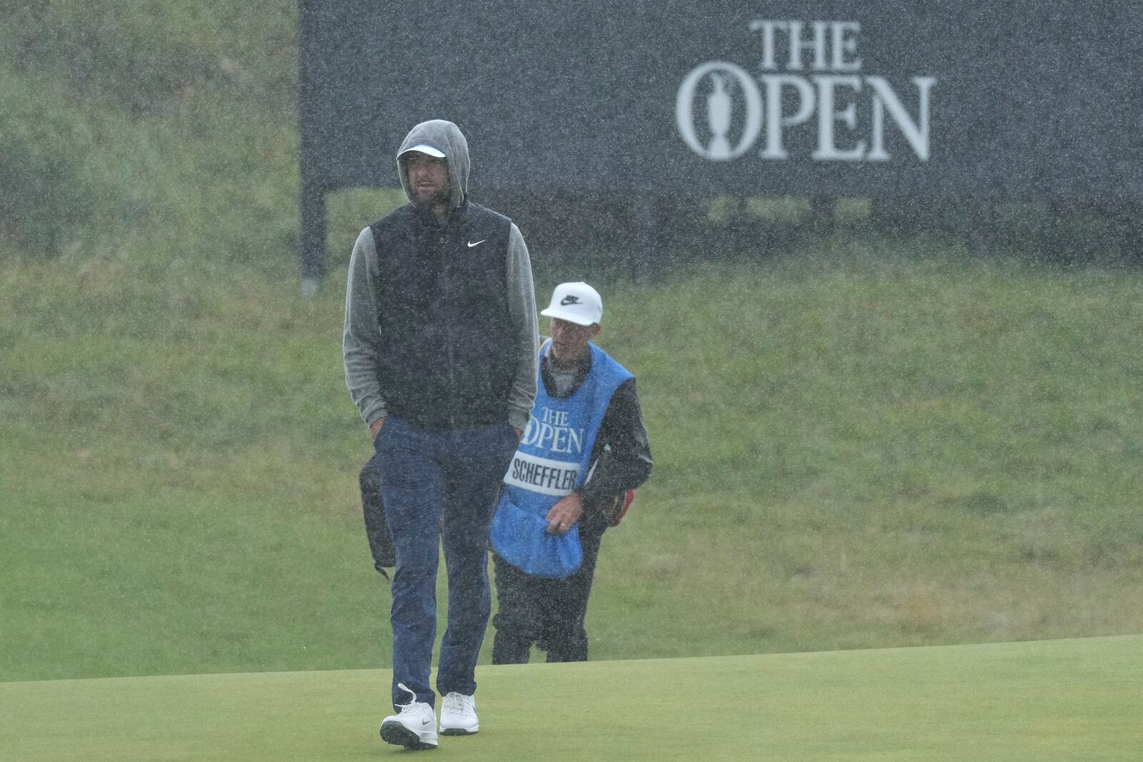 Scottie Scheffler of the United States walks onto the 8th green in heavy rain during a practice round for the British Open golf championship at the Royal Portrush Golf Club, Northern Ireland, Tuesday, July 15, 2025. (AP Photo/Jon Super)