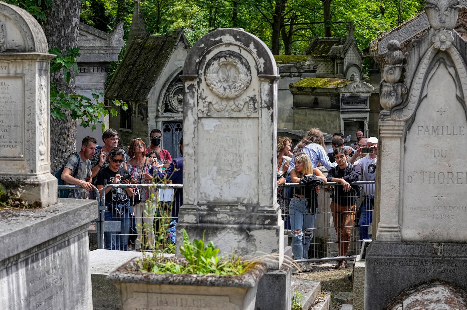 FILE - Fans gather at the tomb of rock singer Jim Morrison at the Pere-Lachaise cemetery in Paris, Saturday, July 3, 2021. Fans across Europe gathered at the grave of rock legend Jim Morrison to mark the 50th anniversary of his death.(AP Photo/Michel Euler, File)