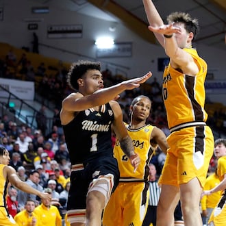 Miami (Ohio) guard Trey Perry (1) dishes off the ball against Western Michigan forward Max Burton during the first half of an NCAA college basketball game, Friday, Feb. 27, 2026, in Kalamazoo, Mich. (AP Photo/Al Goldis)