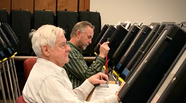 Two elderly seasonal poll workers with the Greene County Board of Elections test rows of voting machines in preparation for early voting.