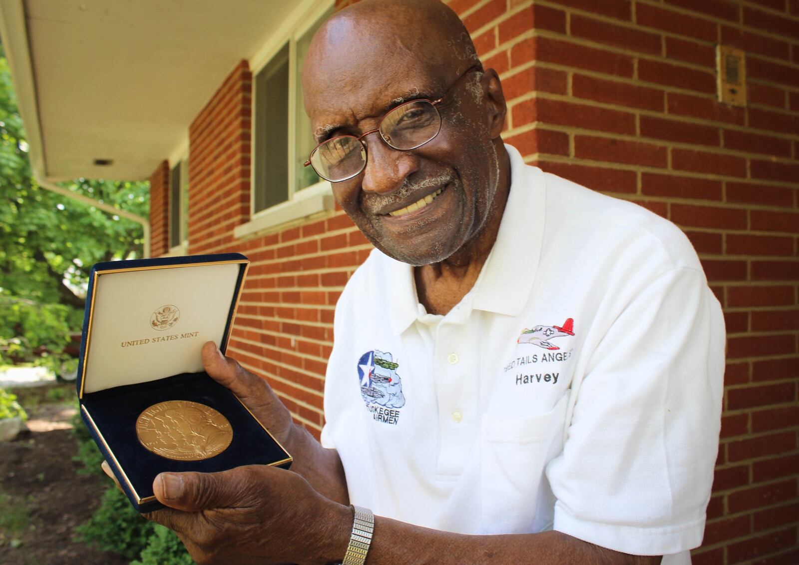 Robert Harvey holds a medal from President Bush for his service as a member of Tuskegee Airmen and having served in World War II.