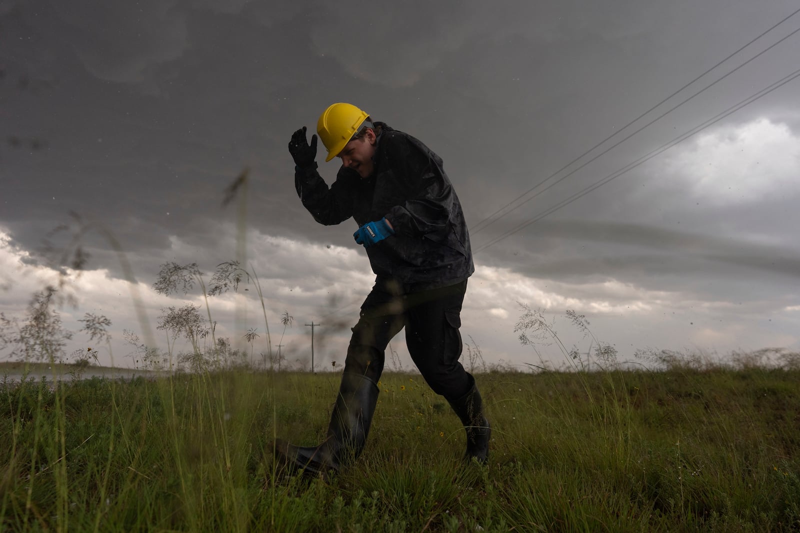 Joey Toniolo ducks from falling hail as he moves back to Northern Illinois University's Husky Hail Hunter vehicle during a Project ICECHIP operation Friday, June 6, 2025, in Morton, Texas. (AP Photo/Carolyn Kaster)
