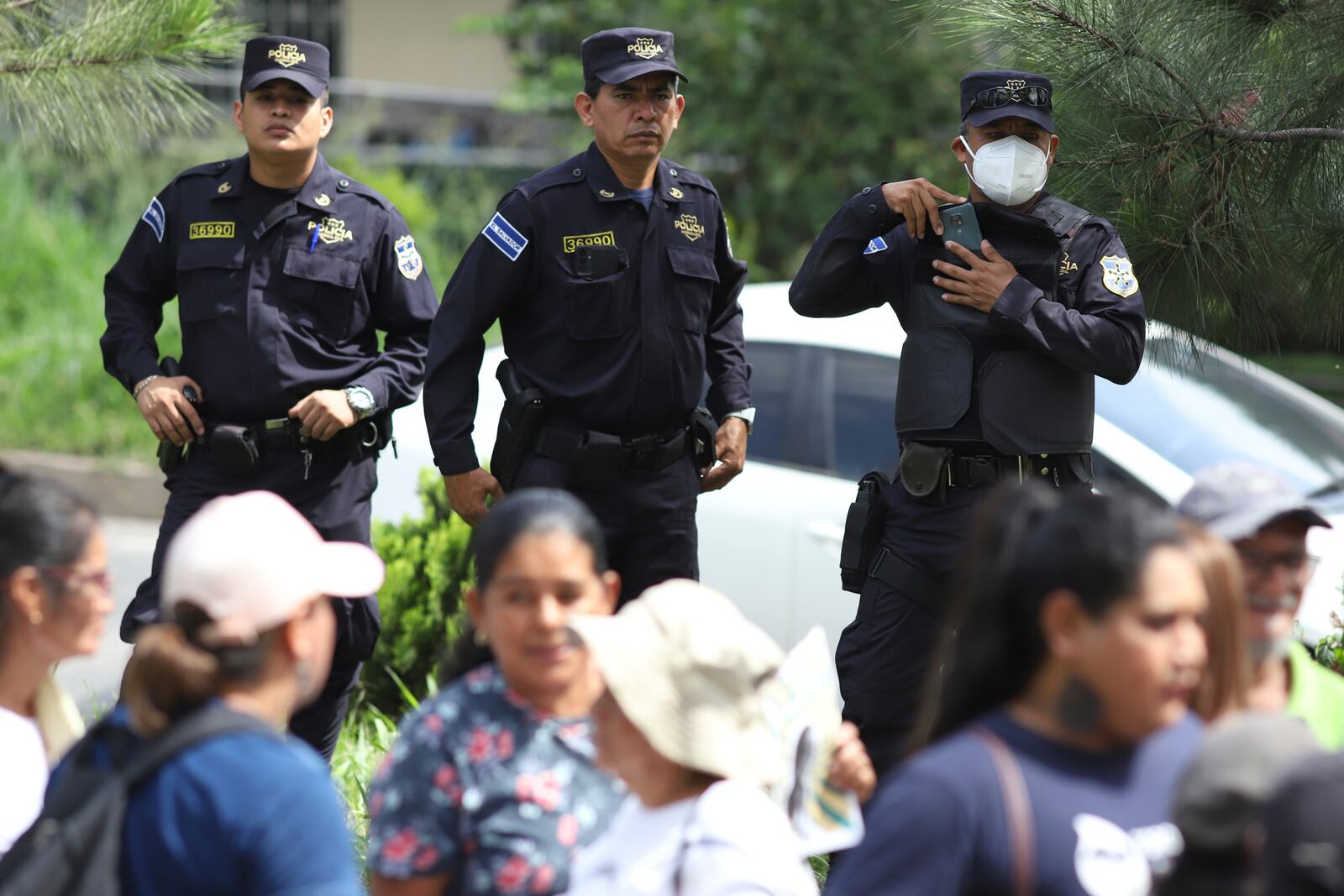 National Police stand behind the relatives of Alejandro Henriquez and Jose Angel Perez outside the courts during the men's hearing in Santa Tecla, El Salvador, Friday, May 30, 2025. The National Civil Police arrested them for protesting near the presidnetial residence. (AP Photo/Salvador Melendez)