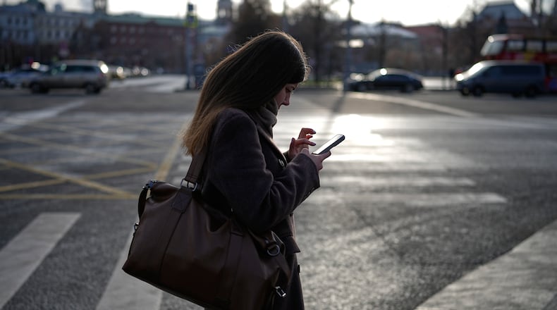 A woman looks at her smartphone in central Moscow, Russia, Thursday, Nov. 20, 2025. (AP Photo/Alexander Zemlianichenko)