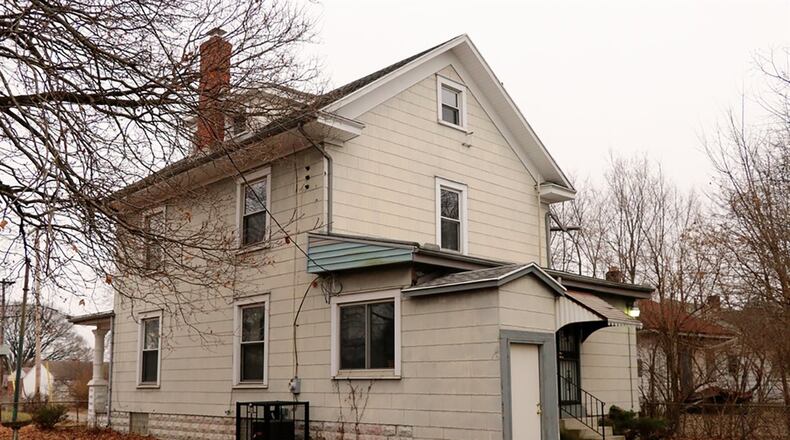 The house sits on a corner lot with a fenced yard with an off-street parking pad or rear patio.