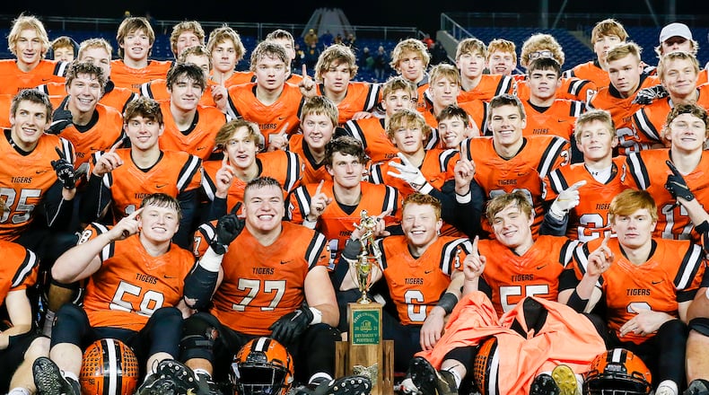 Cutline: The Versailles High School football team poses with the trophy after beating Kirtland 20-16 to win the Division V state championship game on Saturday night at Tom Benson Hall of Fame Stadium in Canton. Michael Cooper/CONTRIBUTED