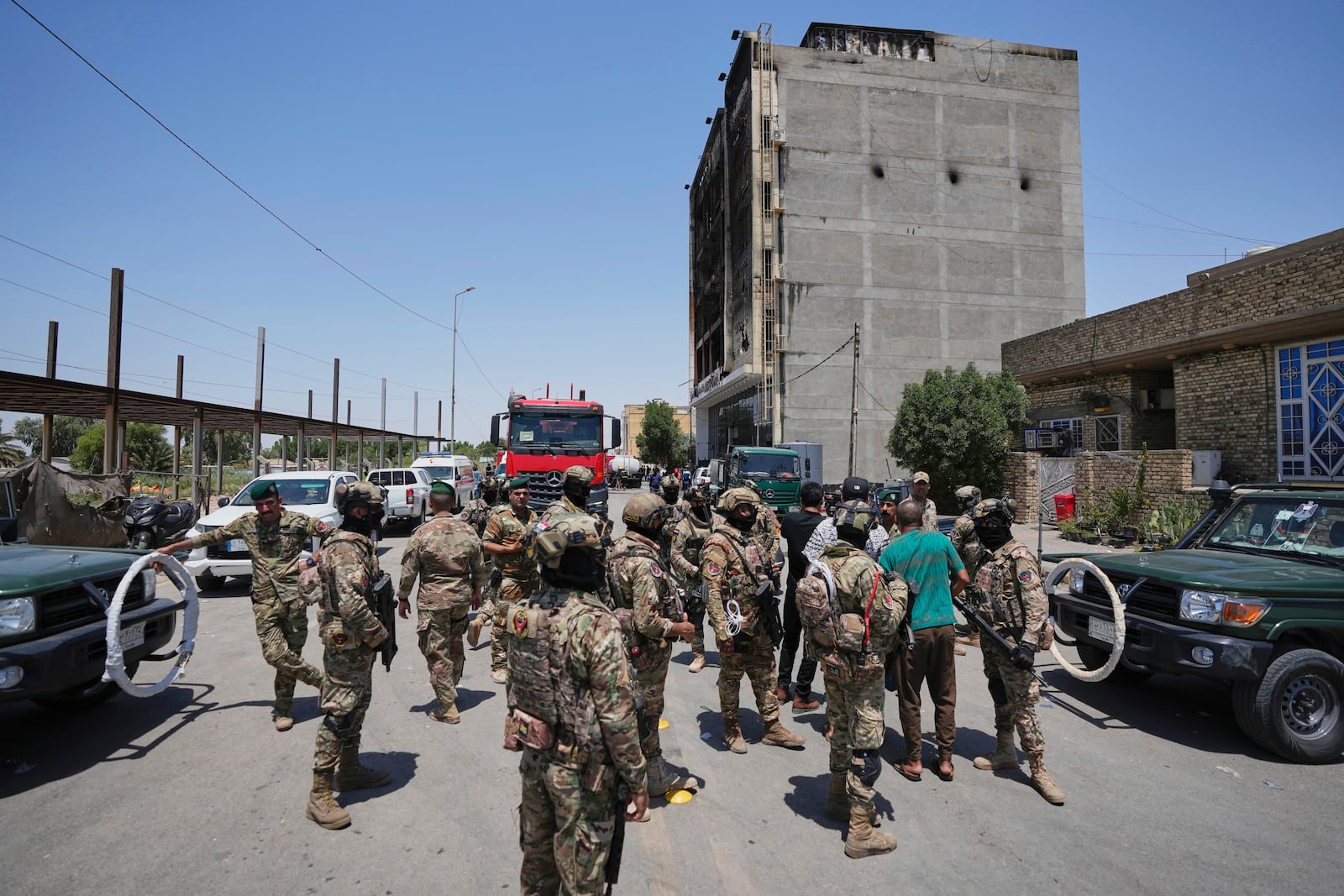 Iraqi security forces gather in front of a burning hypermarket building in Kut, Iraq, Thursday, July 17, 2025. (AP Photo/Hadi Mizban)