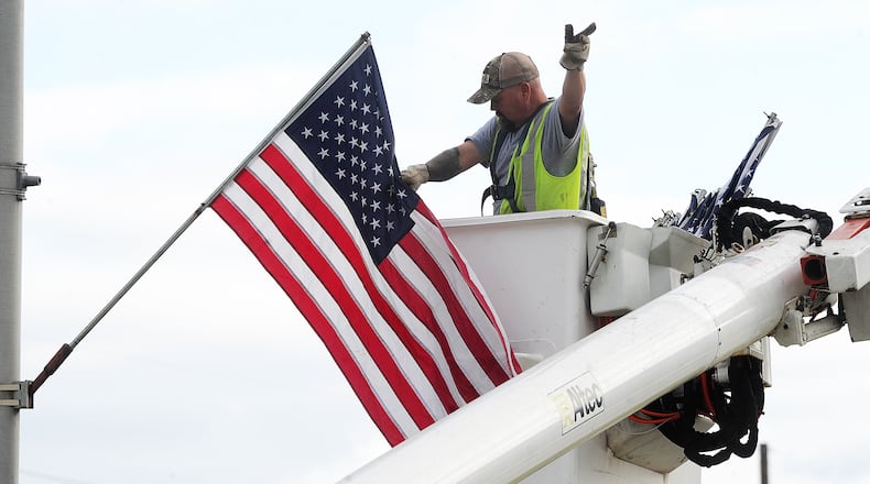 Joe Jenkins, a city of Fairborn employee, places flags along Kauffman Ave. in honor of Flag Day, Wednesday morning, June 14, 2023. MARSHALL GORBY\STAFF
