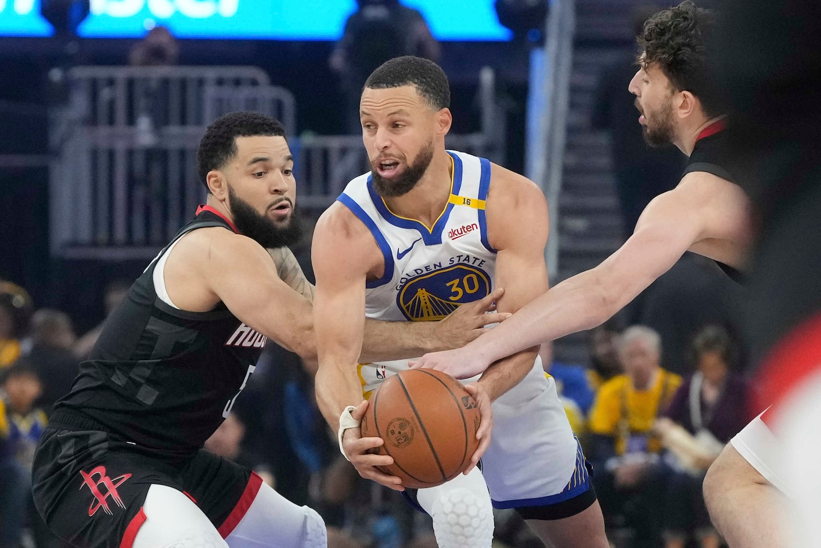Golden State Warriors guard Stephen Curry (30) looks to pass the ball while being defended by Houston Rockets guard Fred VanVleet, left, and center Alperen Sengun during the first half of Game 3 of an NBA basketball first-round playoff series in San Francisco, Saturday, April 26, 2025. (AP Photo/Jeff Chiu)