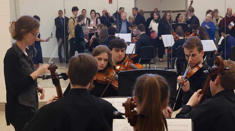 Guests are reflected in a mirror on the wall as they listen to the Oakwood High School Symphonic Band while they tour the new Rick and Jane Schwartz Performing Arts Wing Wednesday, Feb. 7, 2024 following a ribbon cutting ceremony. BILL LACKEY/STAFF