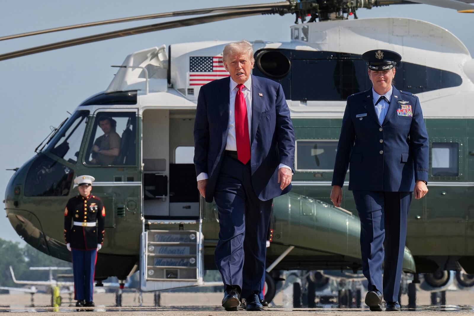 President Donald Trump, escorted by Air Force 89th Air Wing Deputy Commander Melissa Dombrock, walks to board Air Force One at Joint Base Andrews, Md., Friday, July 25, 2025, en route to Scotland. (AP Photo/Jacquelyn Martin)