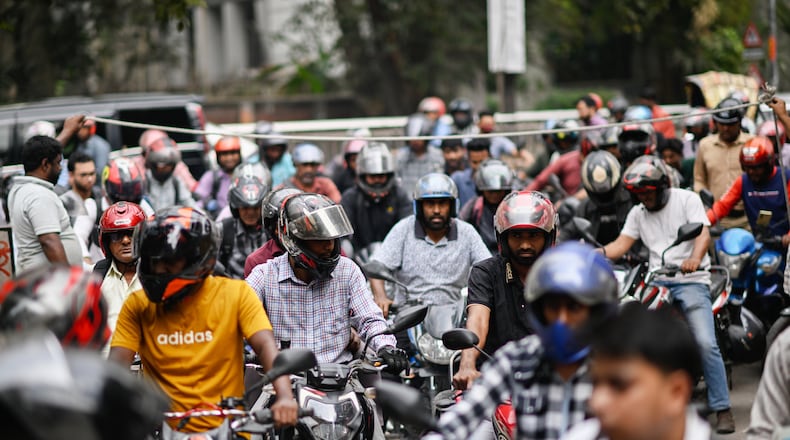 Motorists queue up as others wait behind a rope for their turn to get fuel at a pump, fearing a possible fuel shortage due to the Iran war, in Dhaka, Bangladesh, Sunday, March 8, 2026. (AP Photo/Mahmud Hossain Opu)