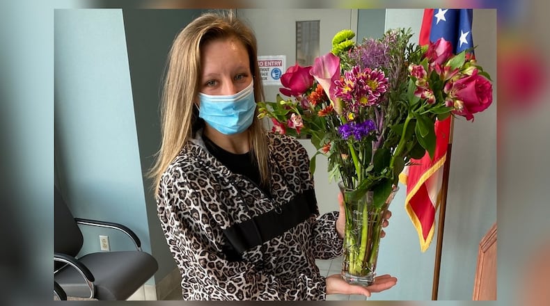 Tiffany Martin of Miamisburg, holds a flower bouquet she received as the recipient of the 2020 Champion of Children Award for her role in bringing a "violent sexual predator" to justice. The award was presented to her Wednesday, Oct. 21, at the office of Montgomery County Prosecutor Mat Heck Jr. CONTRIBUTED