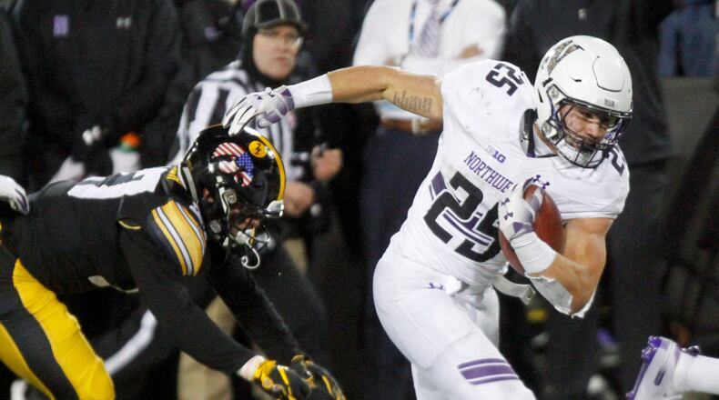 IOWA CITY, IOWA- NOVEMBER 10: Running back Isaiah Bowser #25 of the Northwestern Wildcats breaks a tackle in the second half by defensive back Amani Hooker #27 of the Iowa Hawkeyes, on November 10, 2018 at Kinnick Stadium, in Iowa City, Iowa. (Photo by Matthew Holst/Getty Images)